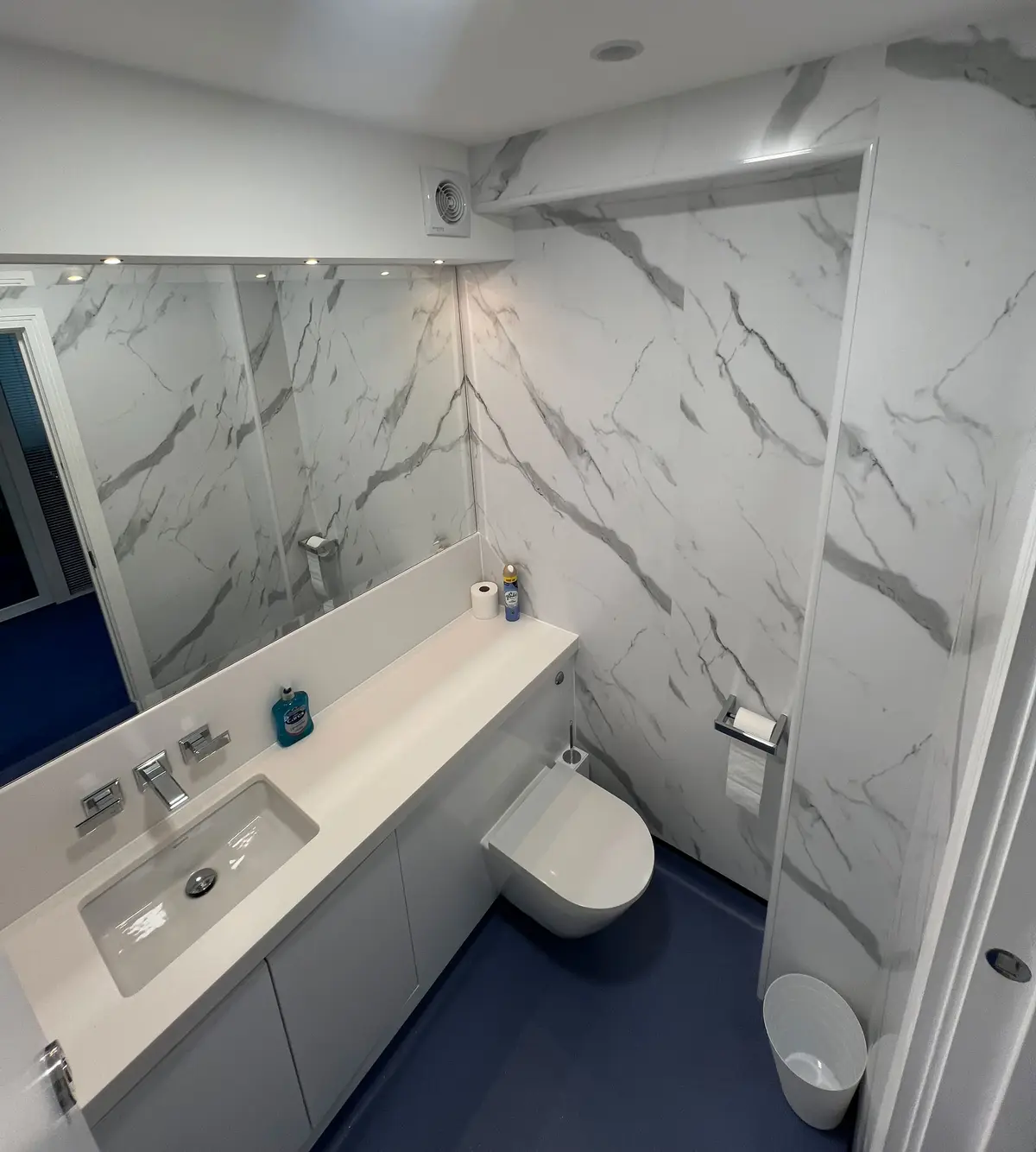 Compact bathroom with vanity unit, mirror cabinet and marble-effect walls