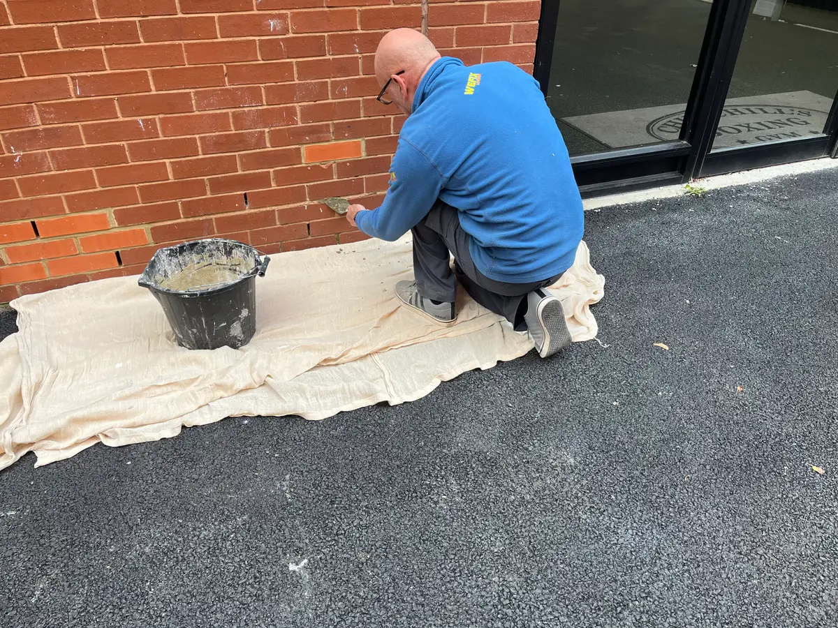 Tradesman repairing exterior brickwork